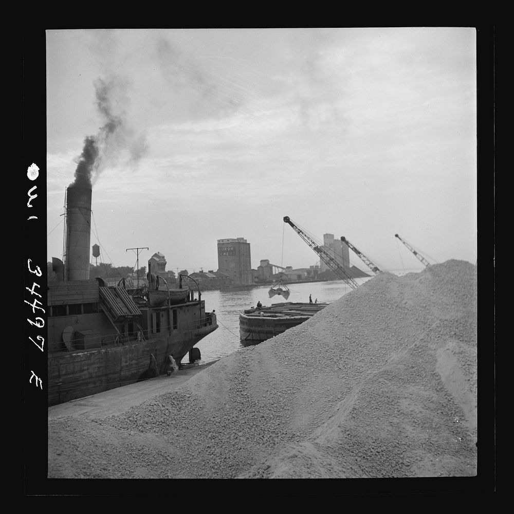Oswego, New York. Unloading bauxite from a barge onto a Canadian boat which has come up through the inland waterways from…