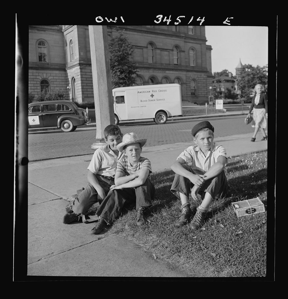 Oswego, New York. Boys recruited to work on the farms during the summer waiting to be picked up by the farmers at 7:30 a.m..…