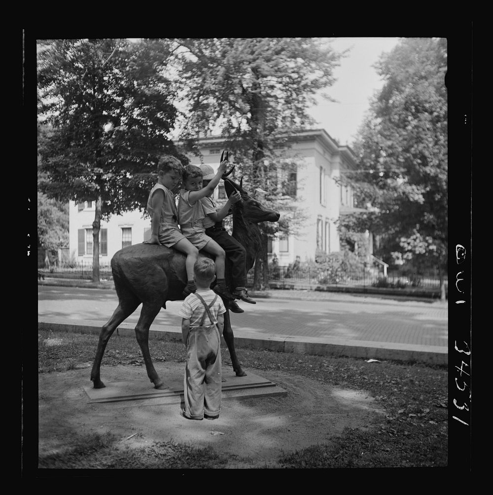 Oswego, New York. Children playing on a bronze elk in front of the Elk's Club. Sourced from the Library of Congress.