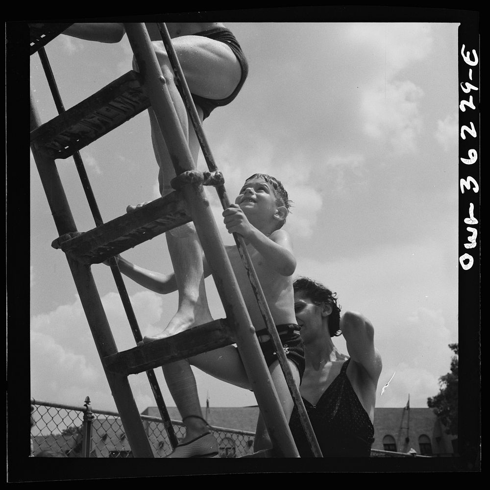 Glen Echo, Maryland. Climbing the ladder to the sliding board at the Glen Echo swimming pool. Sourced from the Library of…