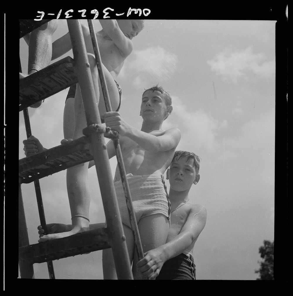 Glen Echo, Maryland. Climbing the ladder to the sliding board at the Glen Echo swimming pool. Sourced from the Library of…
