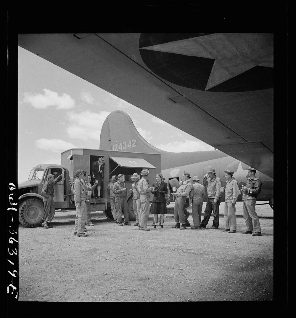 Constantine (vicinity), Algeria. A Red Cross clubmobile serving doughnuts and coffee to the crew of a bomber just returned…
