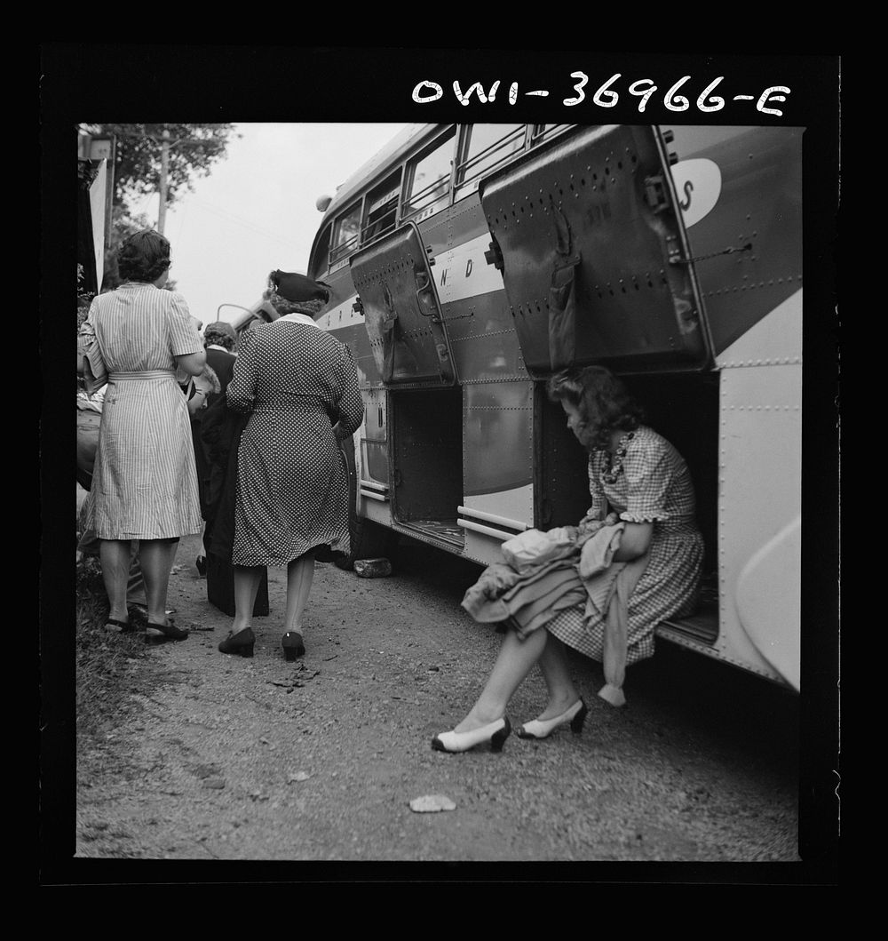 A girl passenger sitting in a baggage compartment while she is waiting for the driver to finish unloading the bags from a…