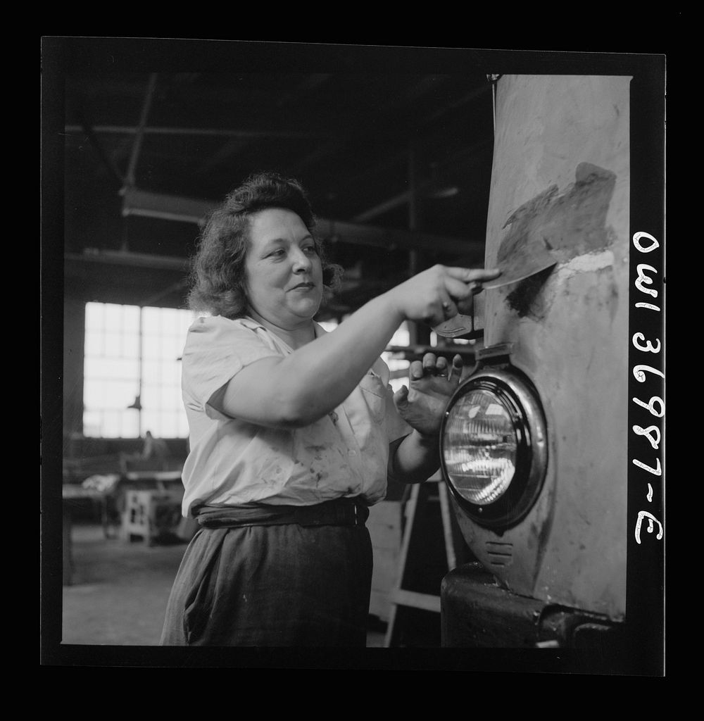 [Untitled photo, possibly related to: Pittsburgh, Pennsylvania. A girl cleaner scraping the paint from a bus which is to be…