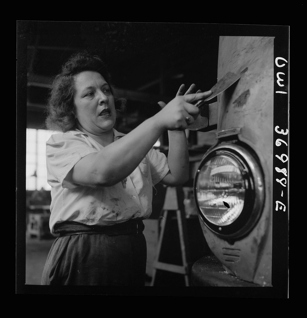Pittsburgh, Pennsylvania. A girl cleaner scraping the paint from a bus which is to be repainted at the Greyhound garage.…