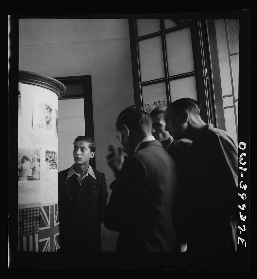 Catania, Sicily. Looking at photos and reading the news of life in Allied countries. This is of particular interest to…