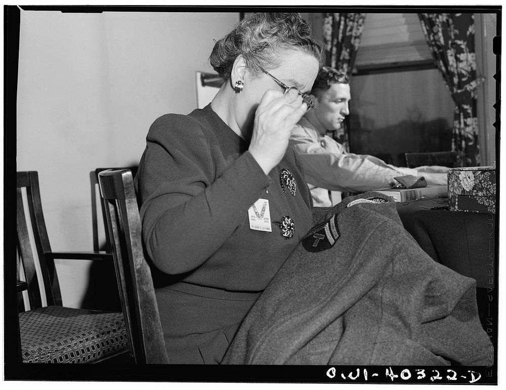 [Untitled photo, possibly related to: Washington, D.C. A volunteer at the United Nations service center sewing insignia and…