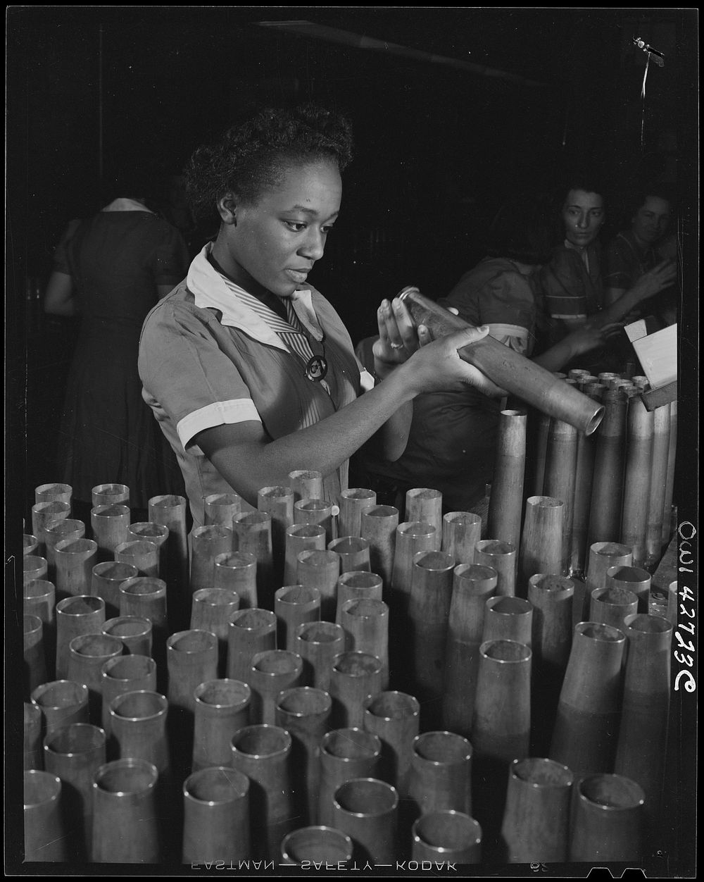 [Frankford Arsenal, Philadelphia, Pennsylvania.] Bertha Stallworth, age twenty-one, inspecting the end of a forty millimeter…