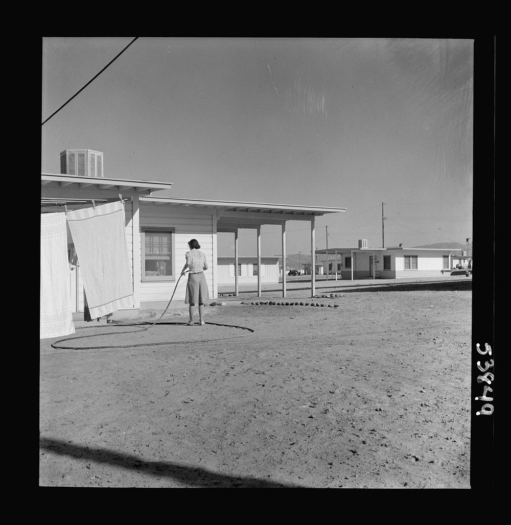 Las Vegas, Nevada. A worker's wife watering a newly planted lawn around one of the thousand demountable houses built…