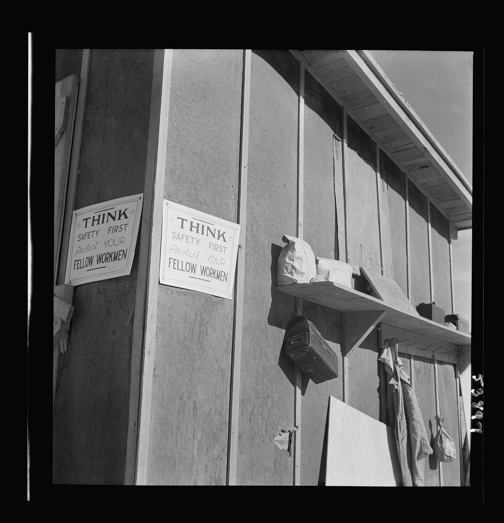 Las Vegas, Nevada. The wall of a tool shed showing a shelf with lunch pails and overalls, and a poster reading "THINK.…