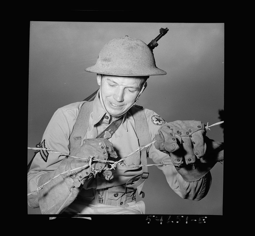 [Untitled photo, possibly related to: Fort Belvoir, Virginia. A soldier handling barbed wire with special gloves which are…