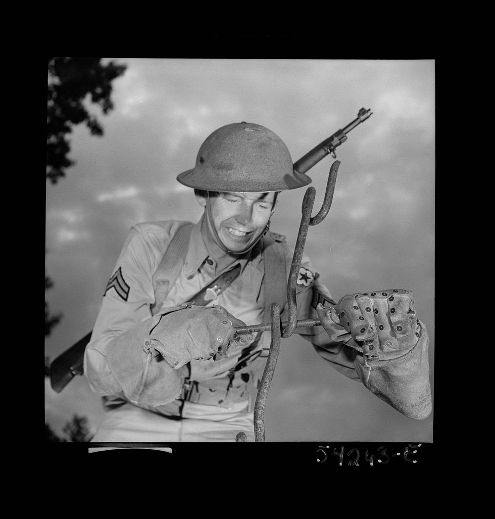 [Untitled photo, possibly related to: Fort Belvoir, Virginia. A soldier handling barbed wire with special gloves which are…