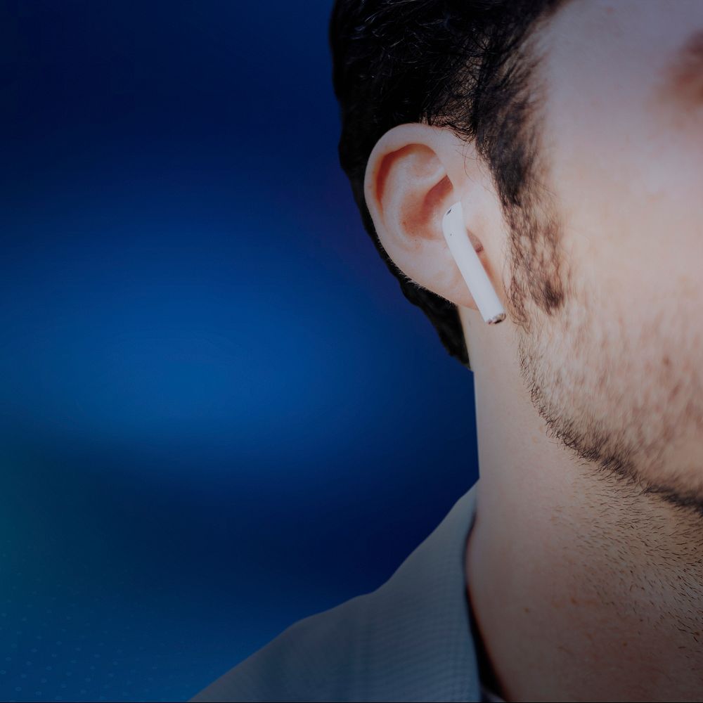 Blue background with American man listening to music on wireless earphones