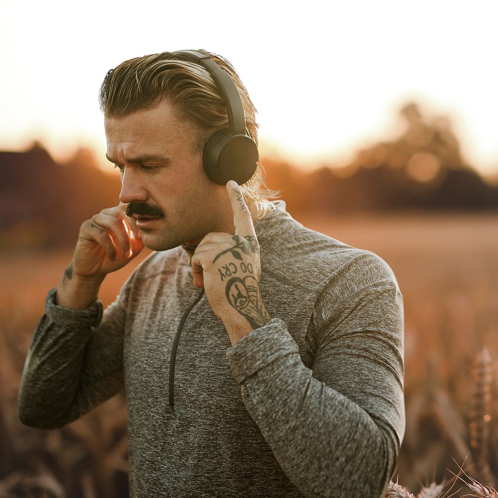 Handsome man wearing wireless headphones in the countryside remixed media