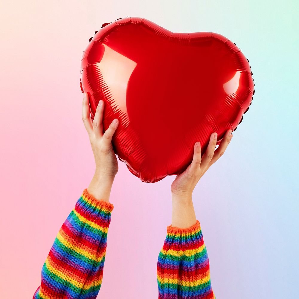 LGBTQ+ community heart balloon held by hands