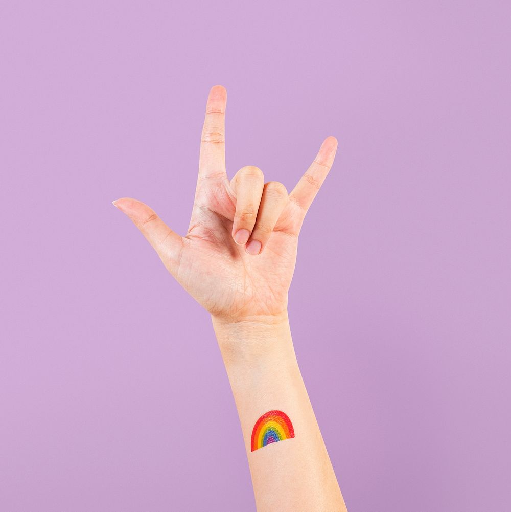 LGBTQ+ pride tattoo with rock n' roll hand in the air