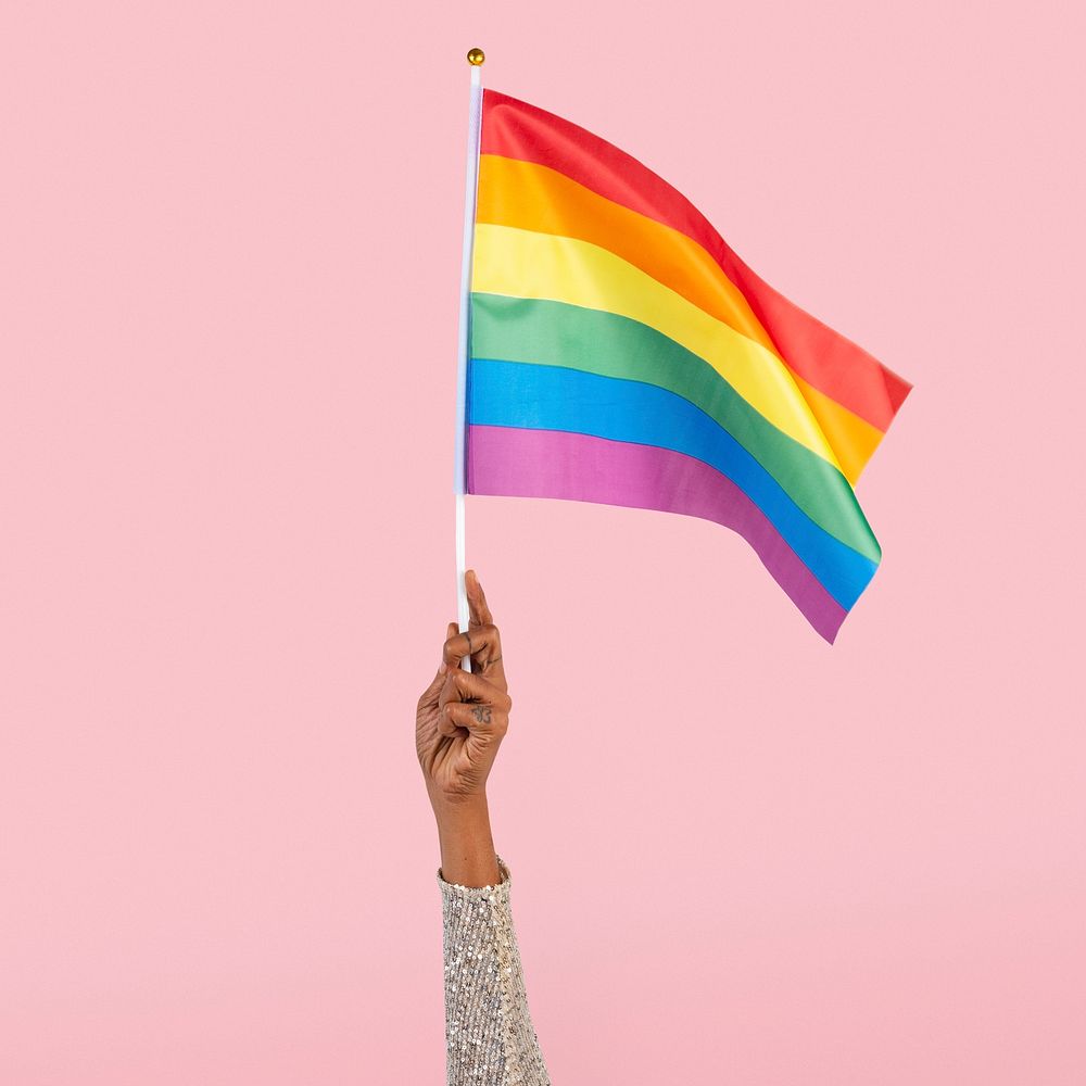 LGBTQ+ pride flag with woman&rsquo;s hand raising