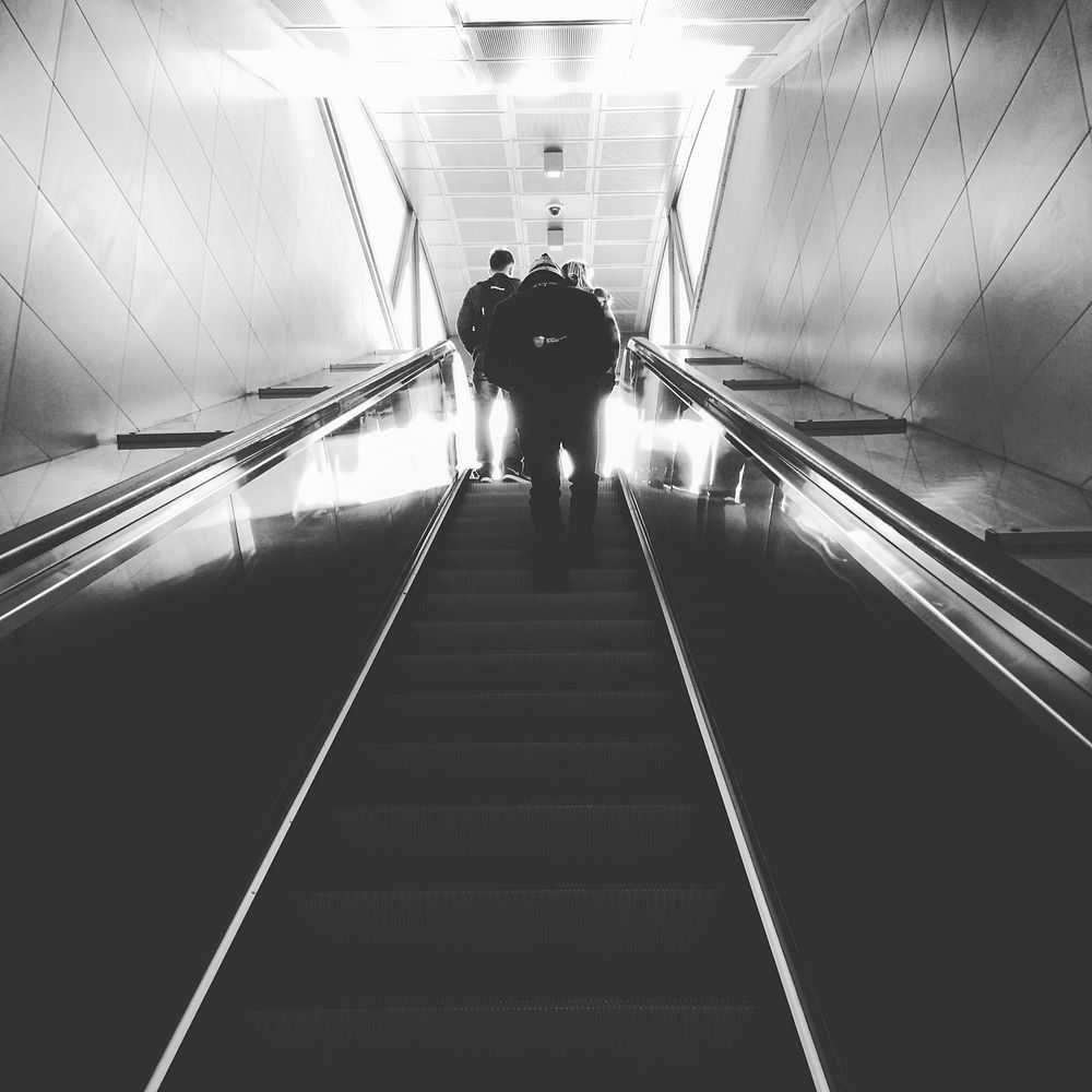 A black-and-white shot of people at the top of an escalator in Portello.. Original public domain image from Wikimedia Commons