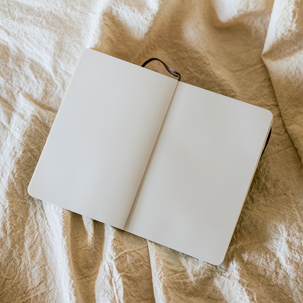 Open notebook on linen blanket in flat lay style