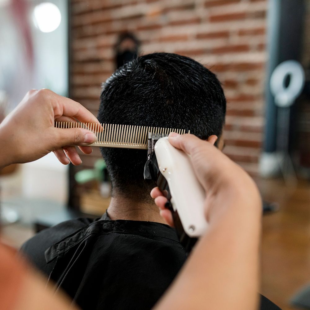 Hairdresser trimming hair of the customer at a barbershop 