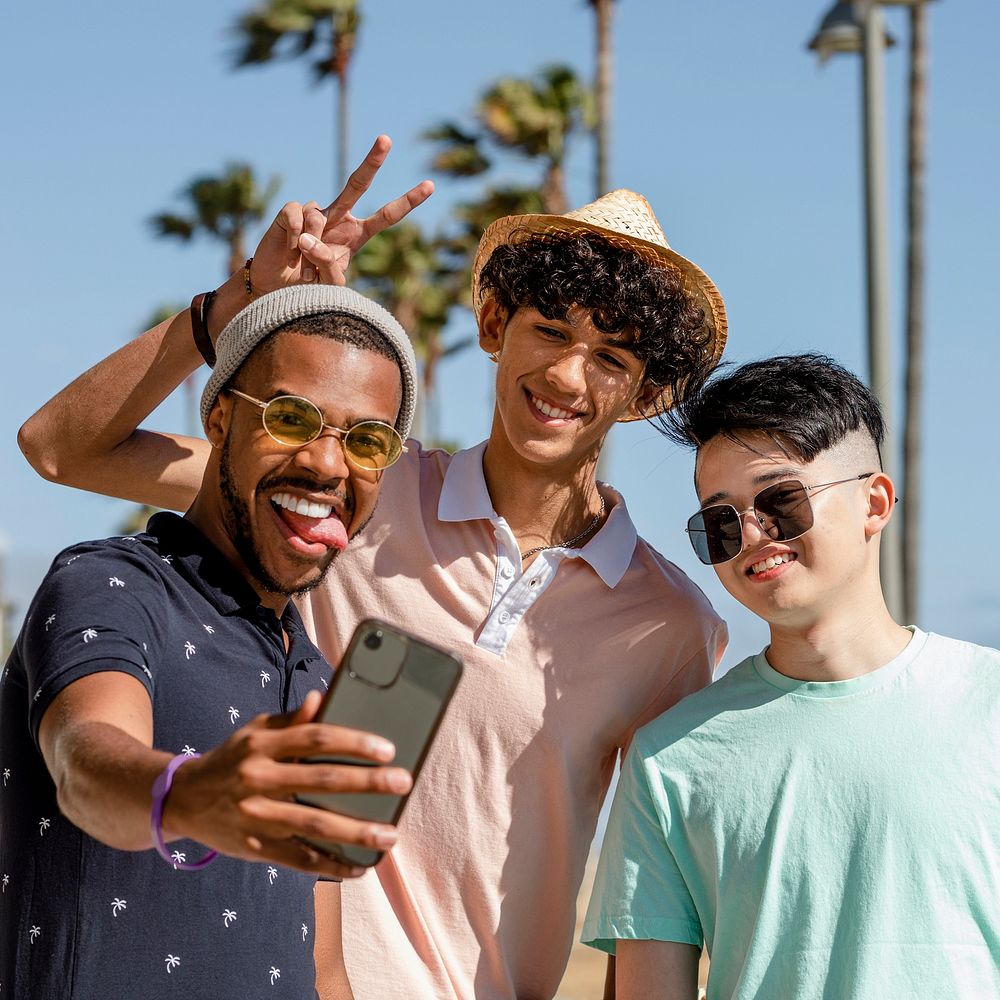 Teen boys taking selfie, enjoying summer together outdoors in Venice Beach, Los Angeles