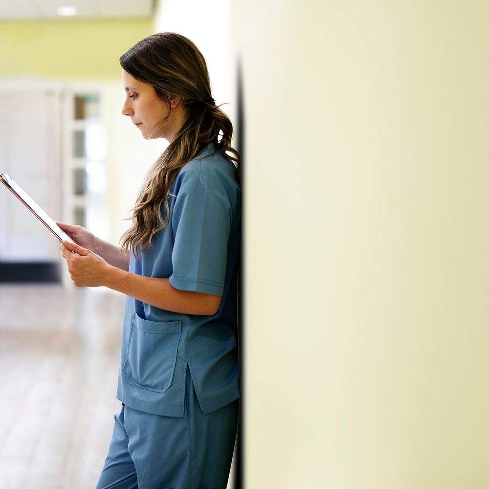 Nurse reading patients record in hallway background