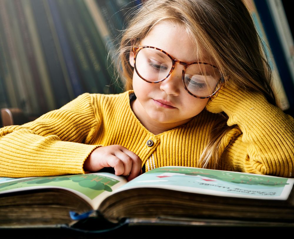Little girl wearing eyeglasses reading a story