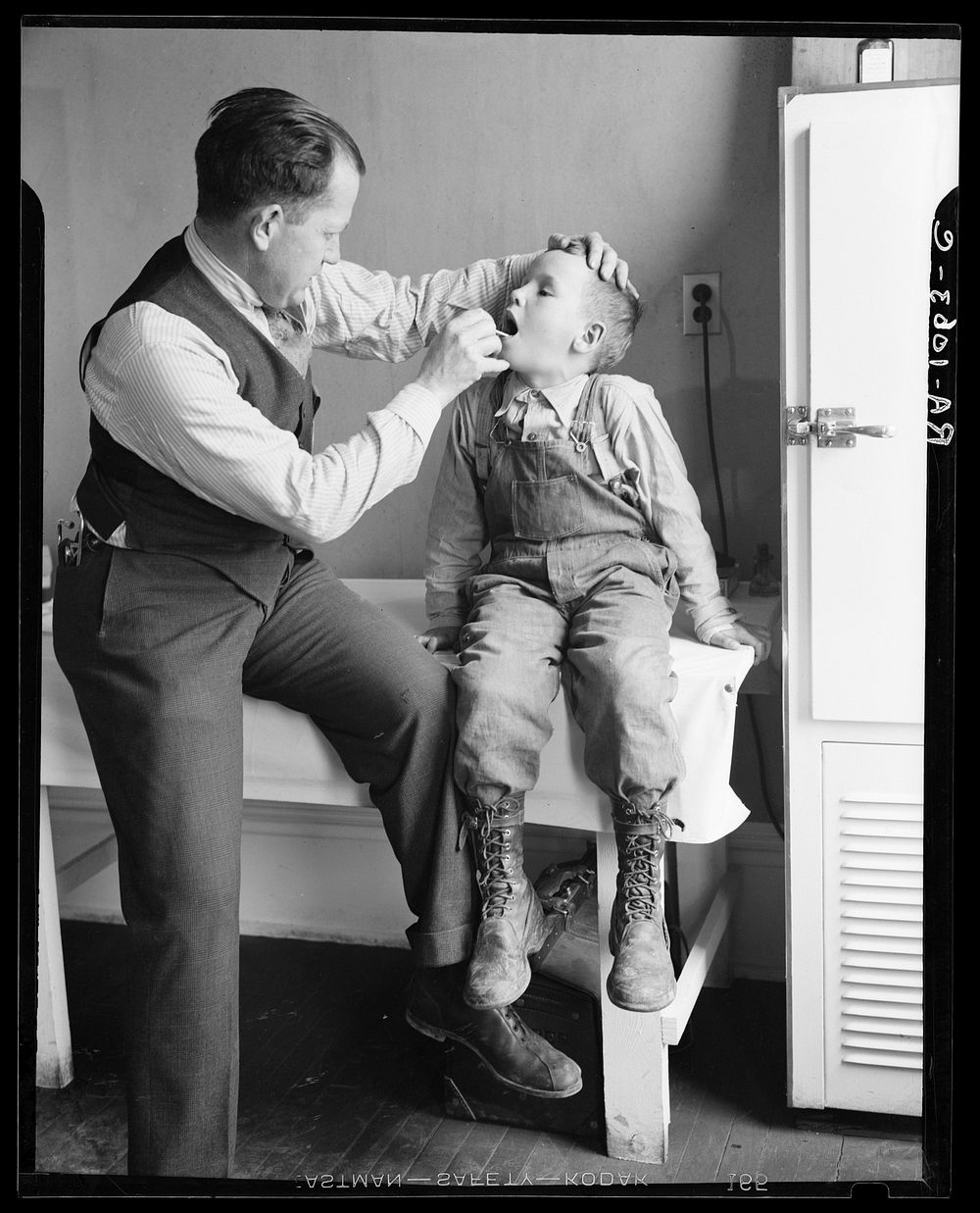 Doctor examining boy's throat. Reedsville, West Virginia. Sourced from the Library of Congress.