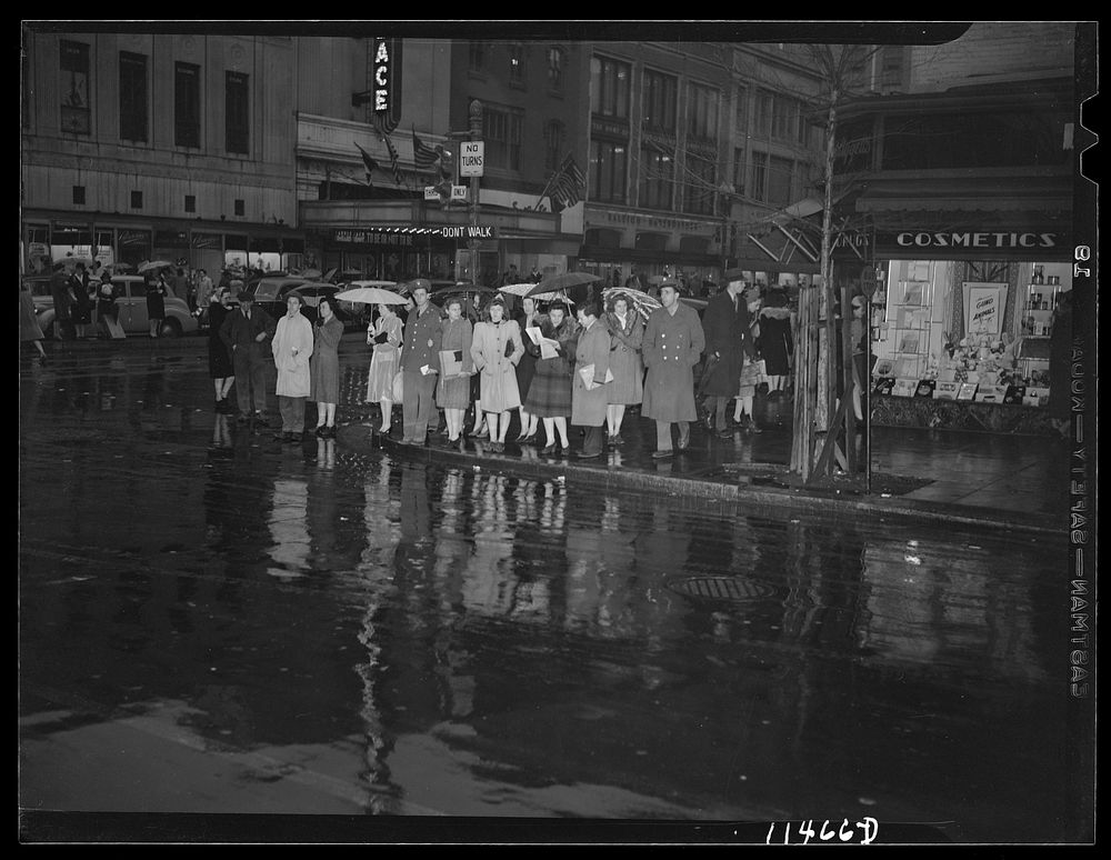 Washington, D.C. People on a rainy night at 13th Street and F Street, N.W. waiting for the "Don't walk" neon traffic light…