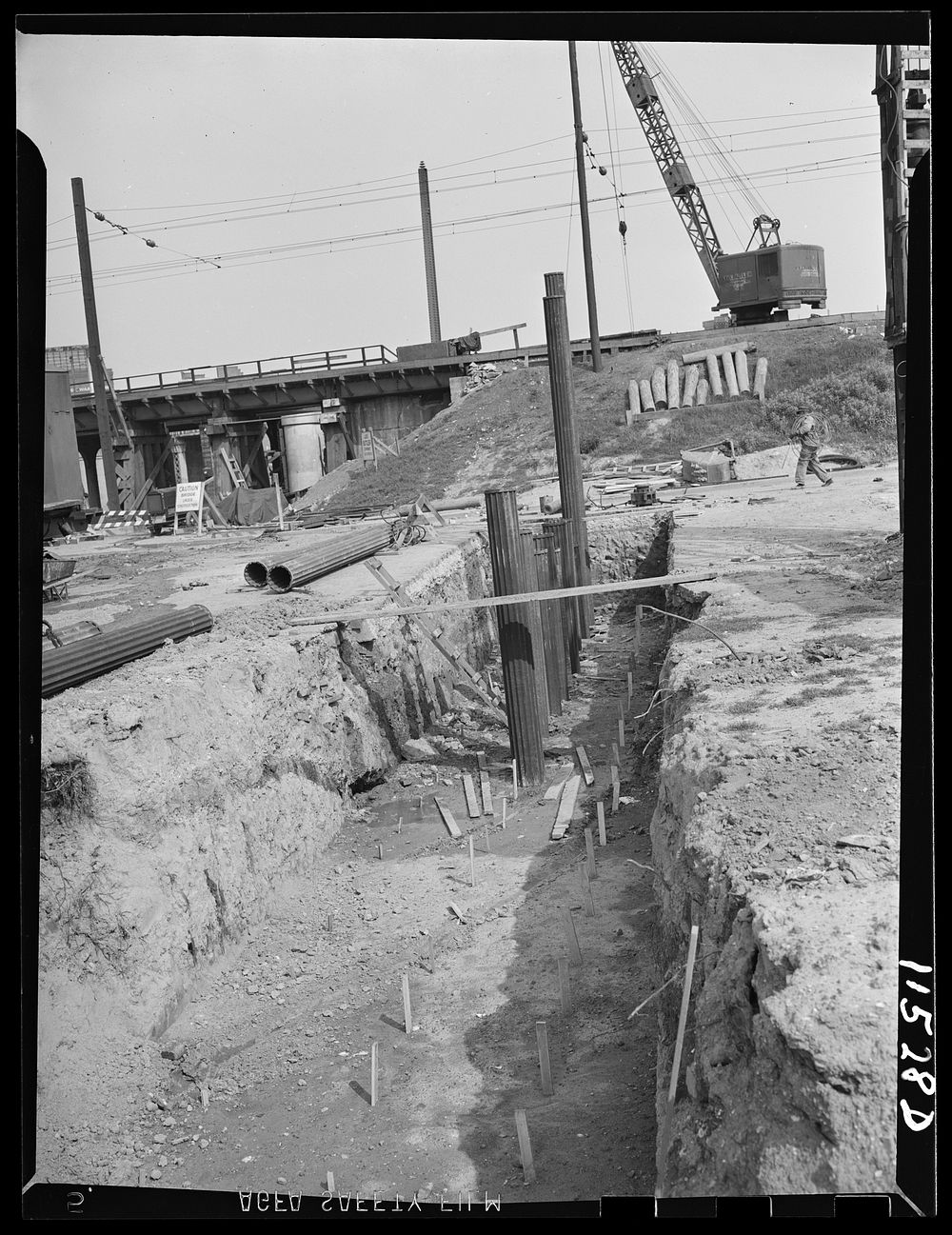 Washington, D.C. Row of piles being driven in a trench. In the foreground are rows of stakes that indicate where other piles…
