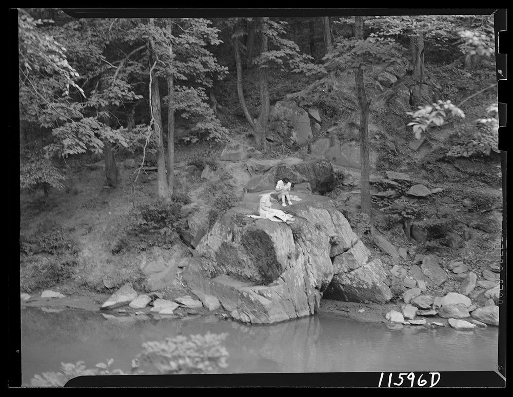 Washington, D.C. Two girls sitting on a large boulder on the bank of Rock Creek writing letters. Sourced from the Library of…