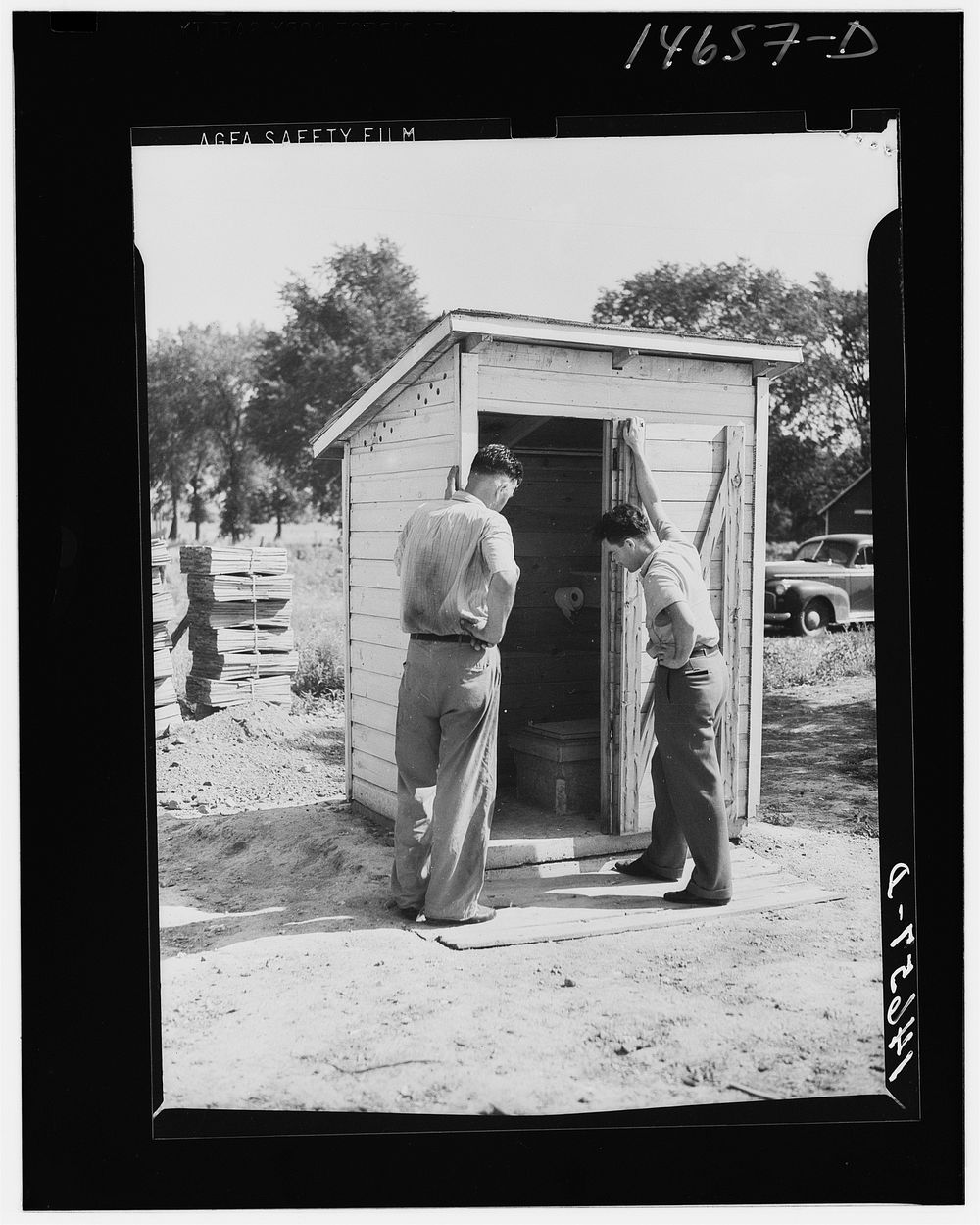 Completed sanitary privy in Minnesota being inspected by farmer and engineer of Farm Security Administration. Minnesota.…