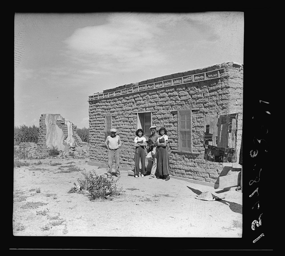 Father and son before their house. Two girls from a neighboring house pose with them. "Those two girls are 'too old' to go…