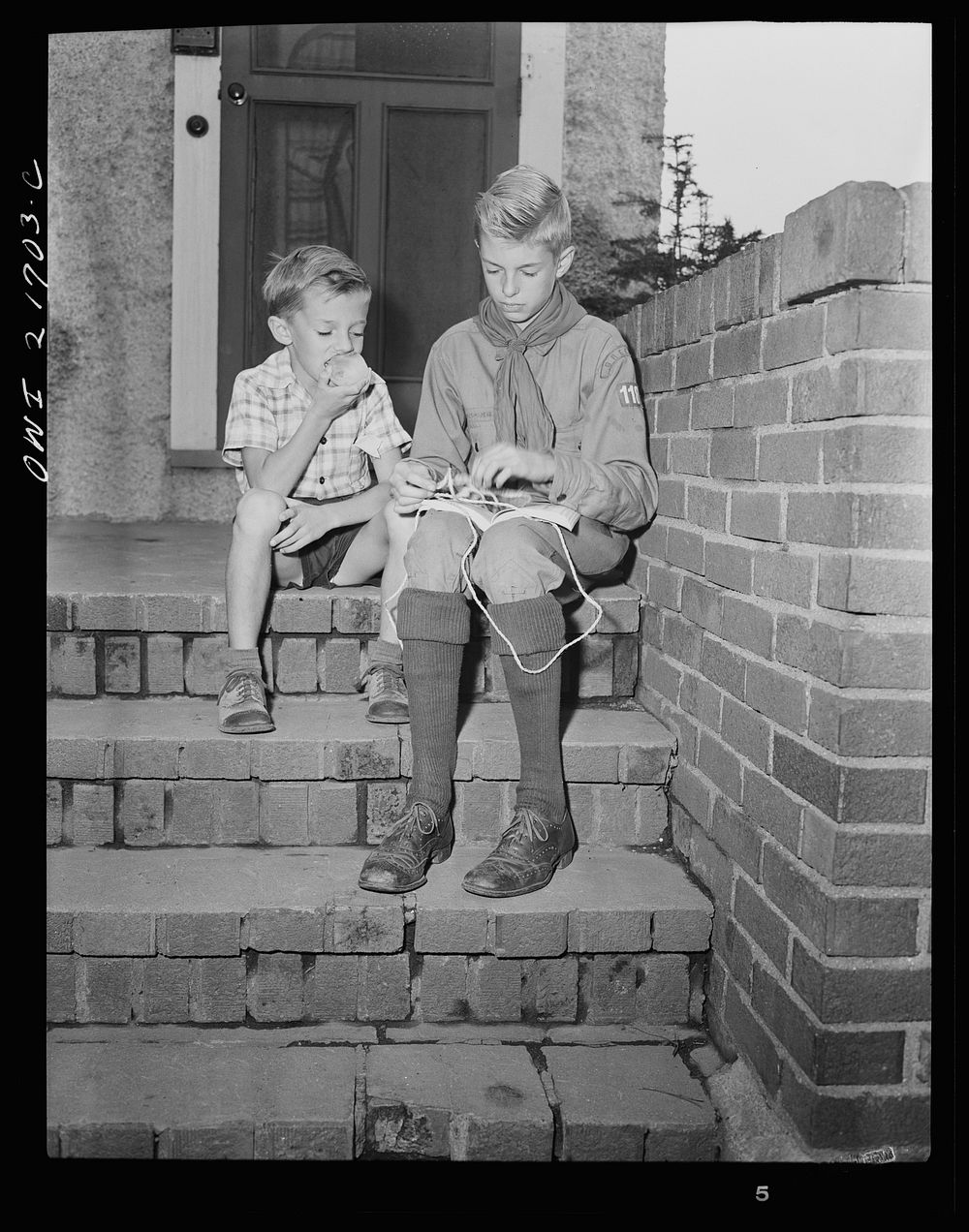 Rochester, New York. Earl Babcock watching while Howard, his brother, in his Boy Scout uniform, practices tying knots.…