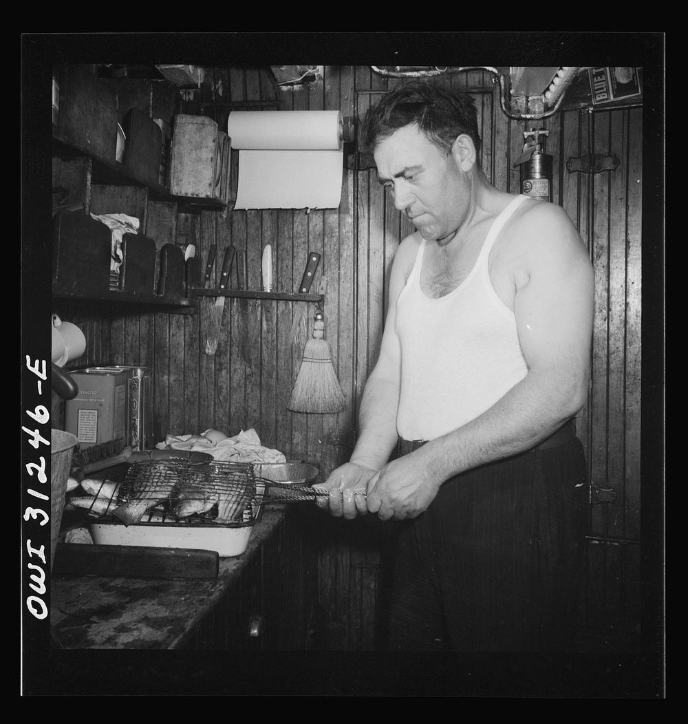 On board the fishing boat Alden, out of Gloucester, Massachusetts. Ship's cook preparing to broil freshly-caught mackerel…