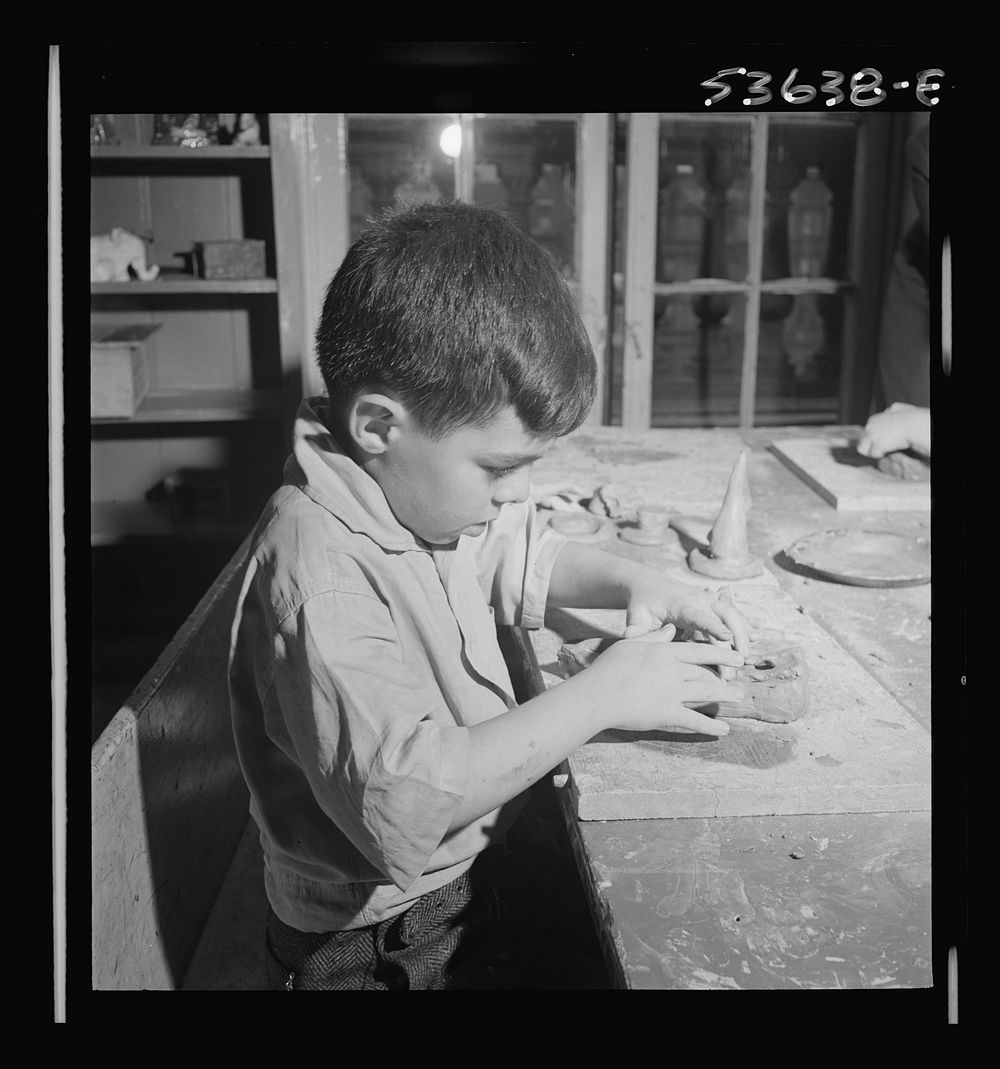 New York, New York. A small boy enjoying his work in clay at Greenwich House where he receives day care while his mother…