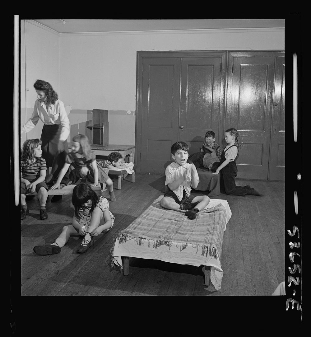New York, New York. Children putting on their shoes after a rest period at Greenwich House where they receive day care while…