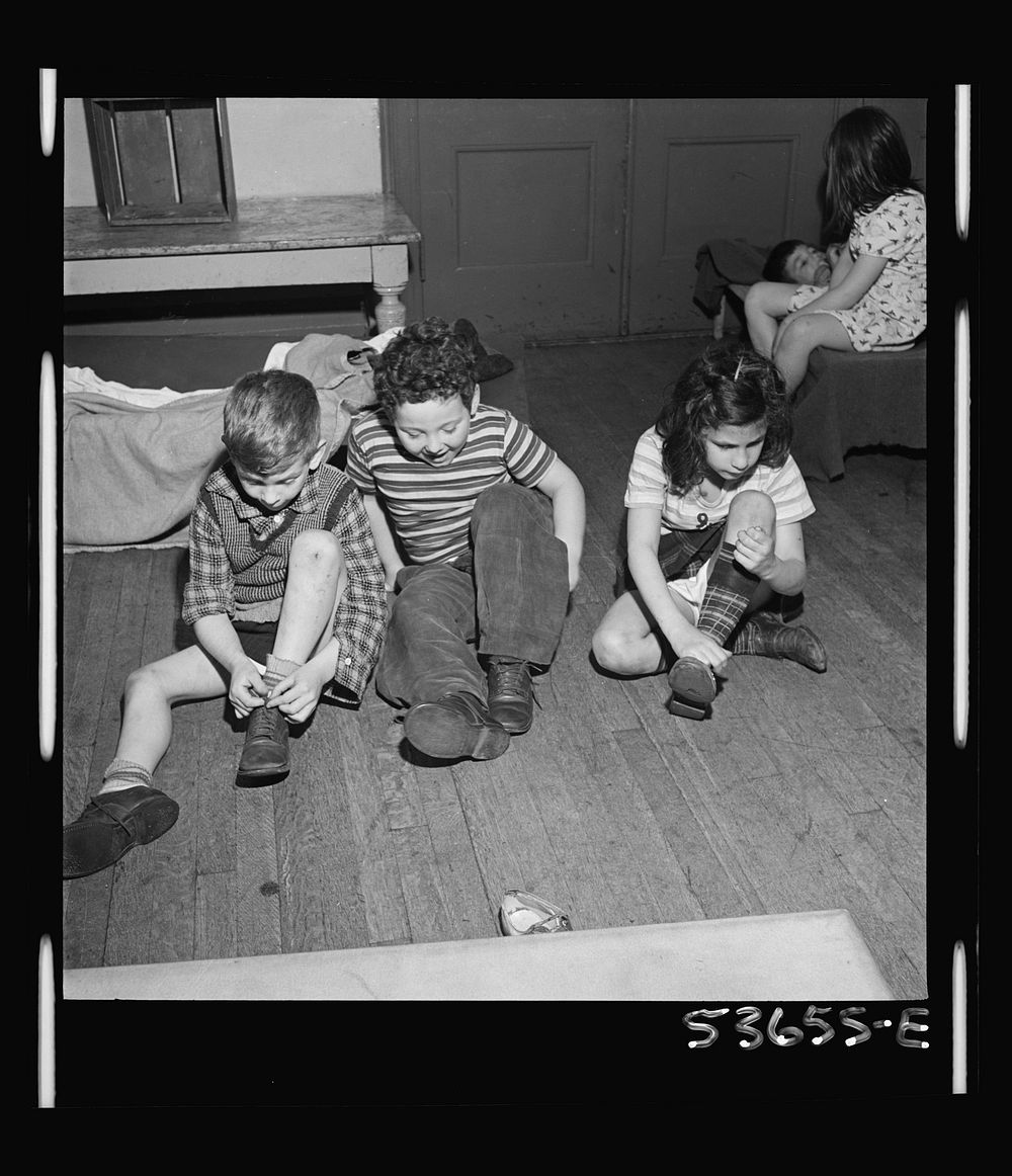 New York, New York. Children of the nursery school group at Greenwich House putting on their shoes after a rest period which…