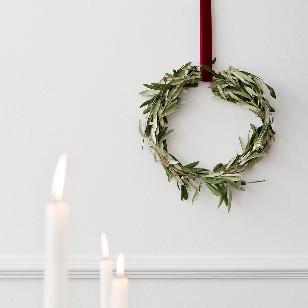 Christmas wreath on a white wall with lighted white pillar candles