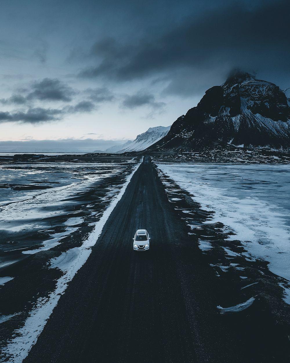 Car driving down a black road on the Icelandic coast