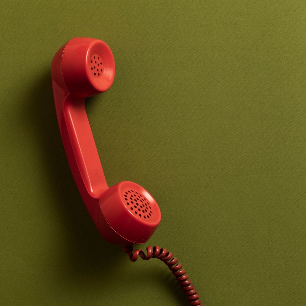Retro red corded phone on an olive green background 