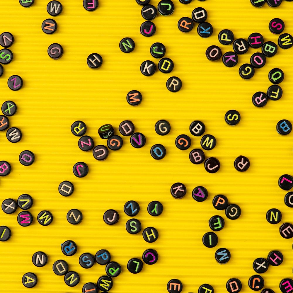Black alphabet beads yellow wallpaper background