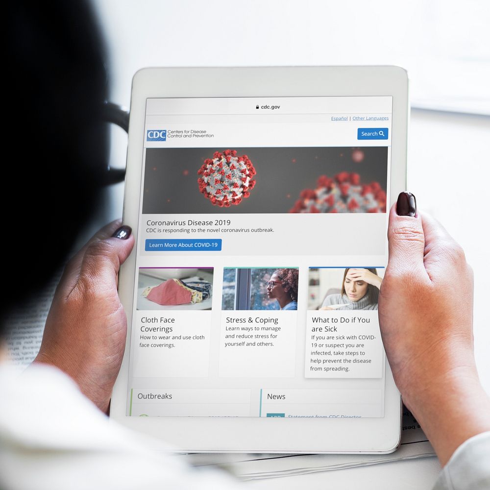 Woman reading coronavirus updates from a tablet mockup with editorial graphic from https://www.cdc.gov accessed on April 8th…