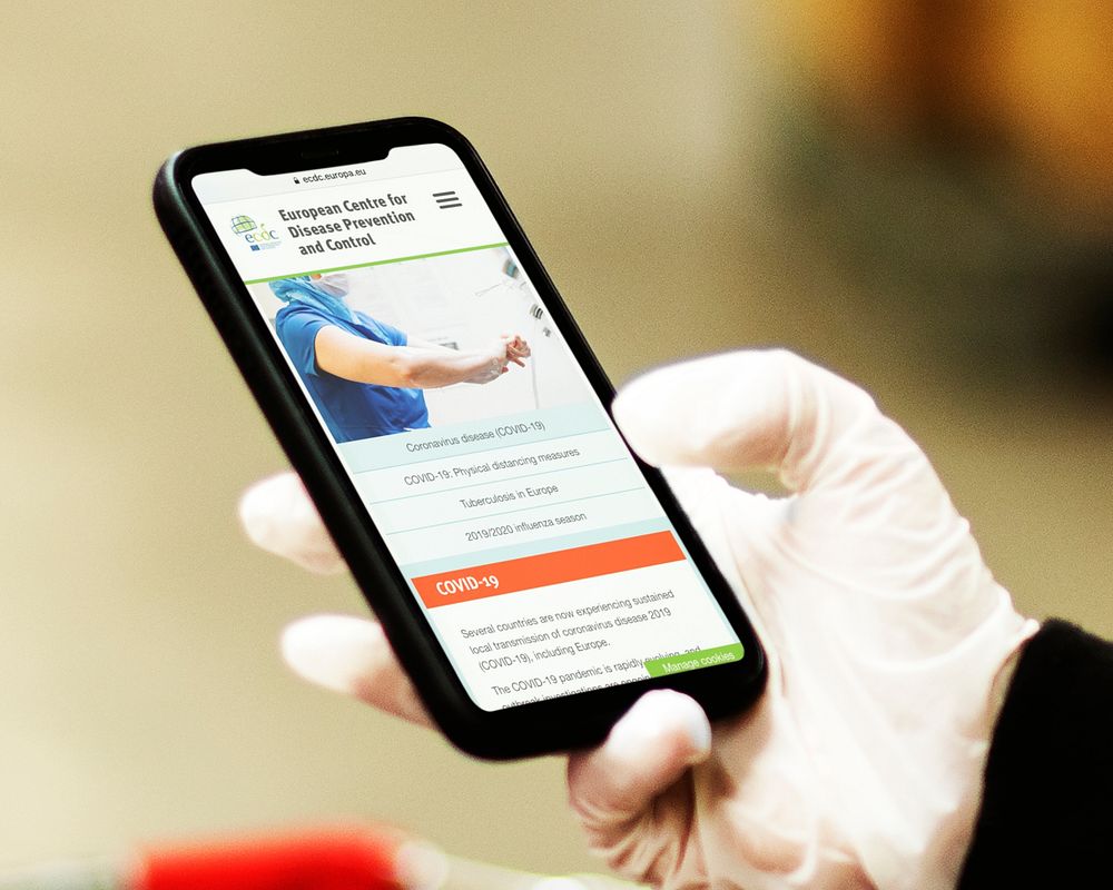 Man reading coronavirus information from a phone mockup with editorial graphic from https://www.ecdc.europa.eu/en accessed…