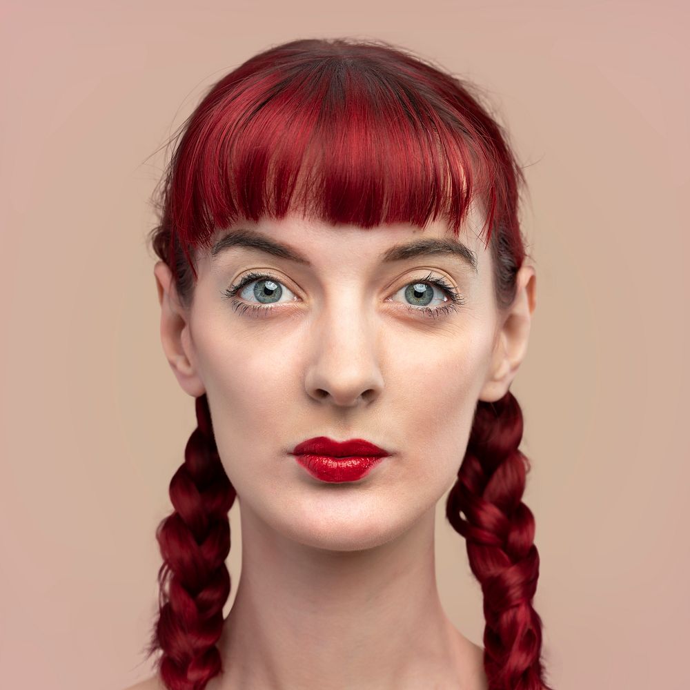 Portrait of beautiful woman with braided red hair on a blank beige wall