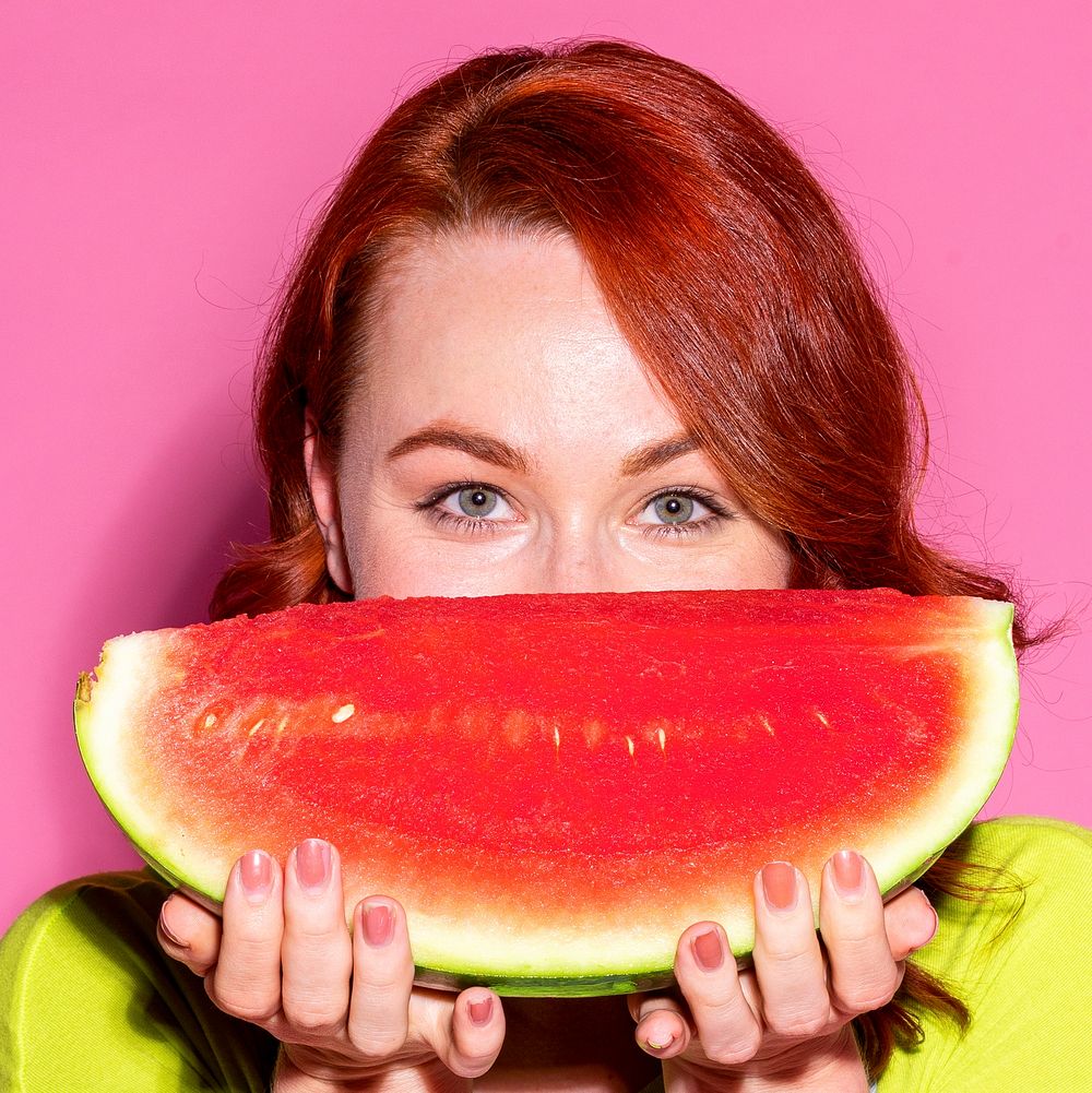 Woman holding a watermelon over her mouth 