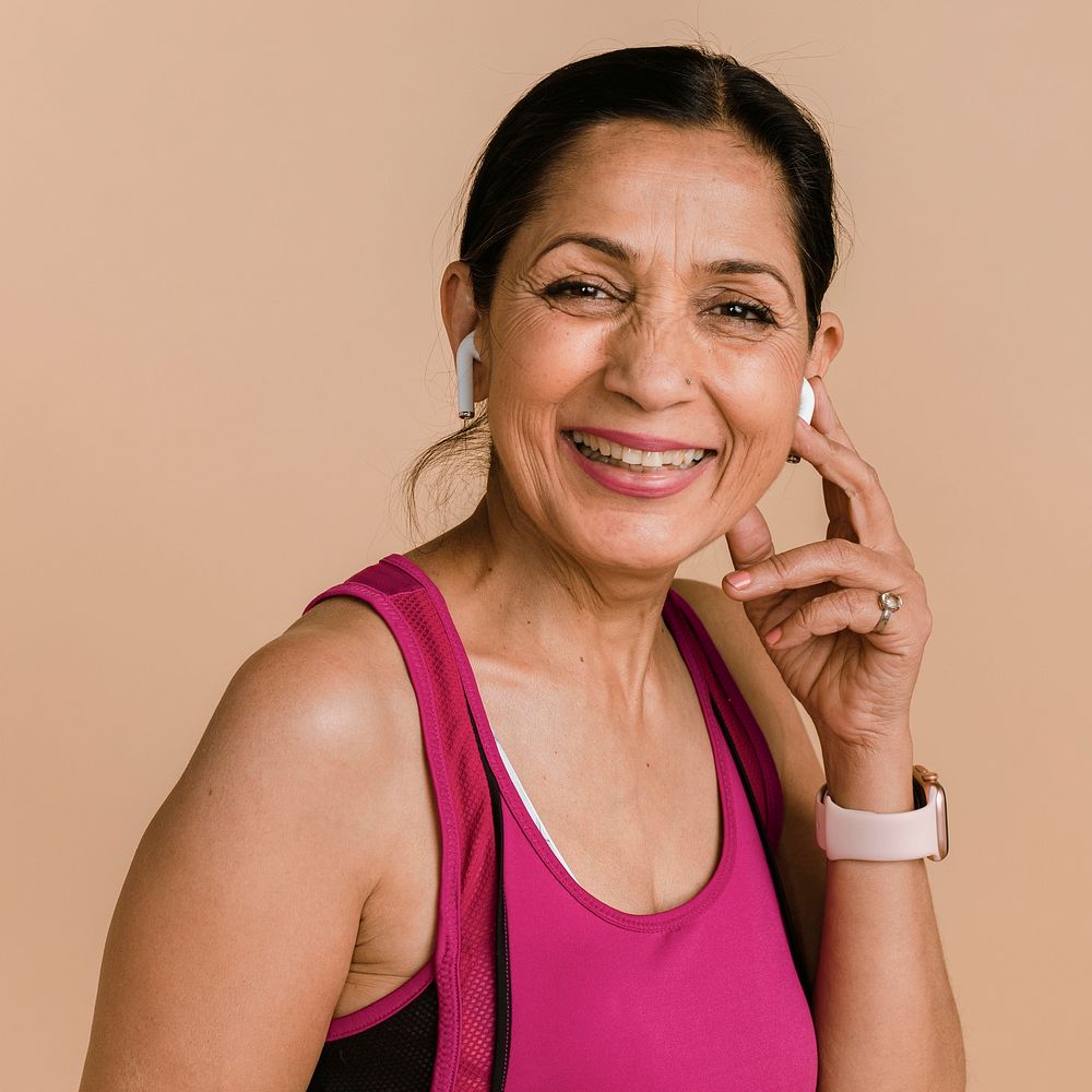 Sporty Indian woman listening to music with wireless earphones 
