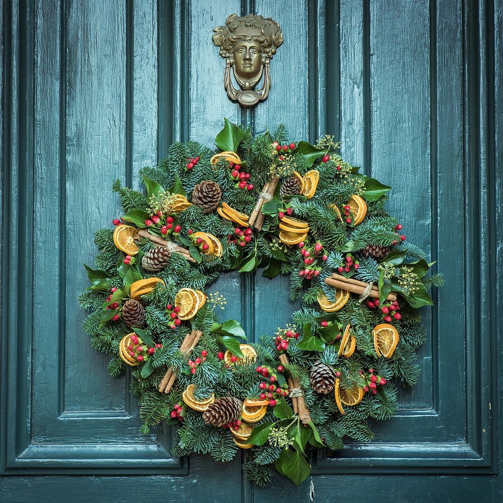 A festive, fall foliage wreath hangs on a dark, green door. Original public domain image from Wikimedia Commons