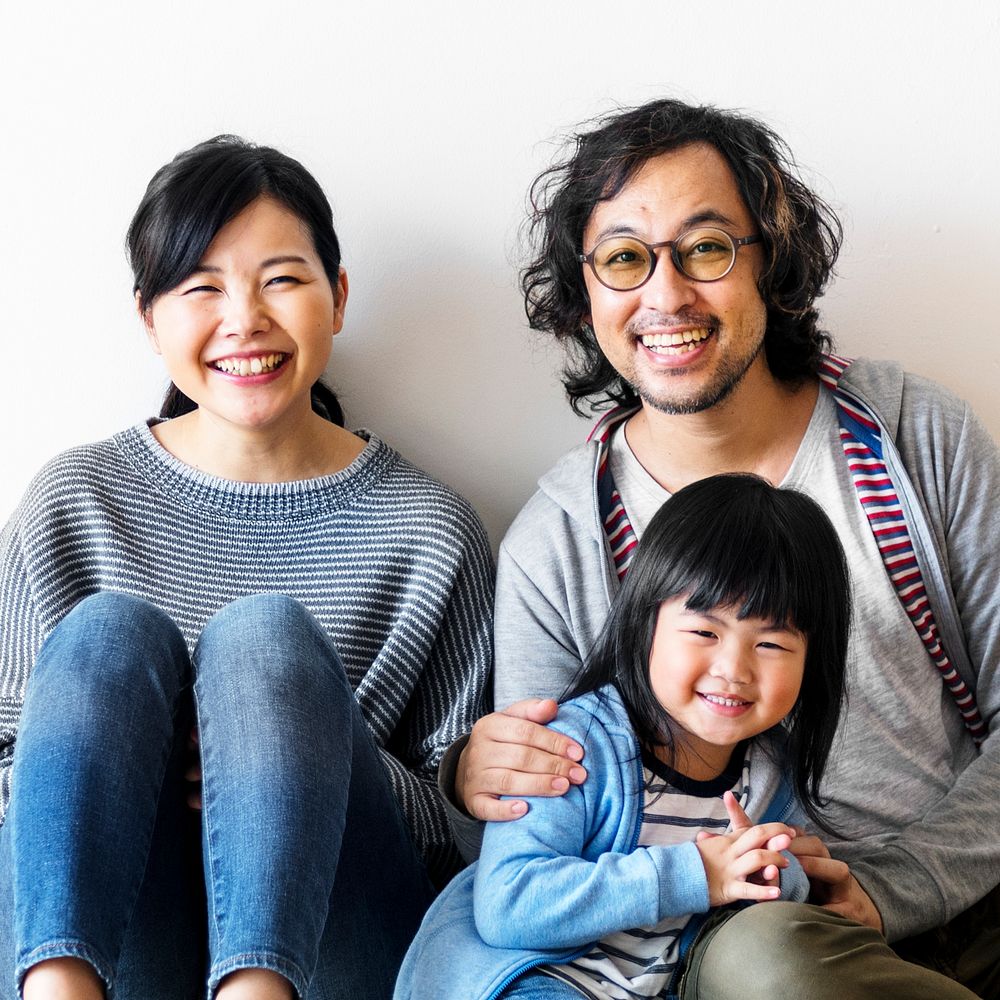 Smiling Asian family with a daughter sitting on the floor