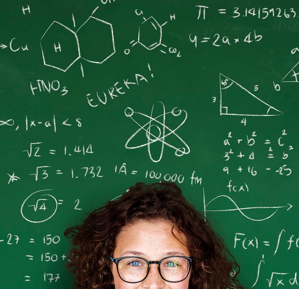 Smart girl with formulas on blackboard